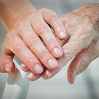 Younger person holding the hand of an older person