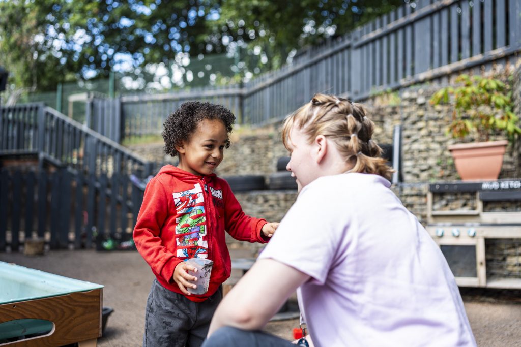 A teacher and child having a conversation in the playground