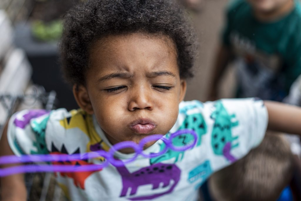 A child putting effort in to blow into a bubble wand